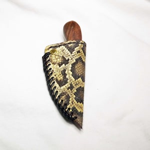 May include: A small knife with a wooden handle and a snakeskin sheath. The sheath is brown with a black stitching detail.