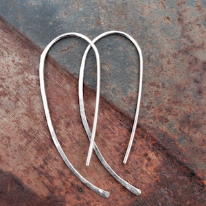 May include: A pair of silver hoop earrings with a hammered texture. The earrings are simple and elegant, and would make a great gift for any occasion.