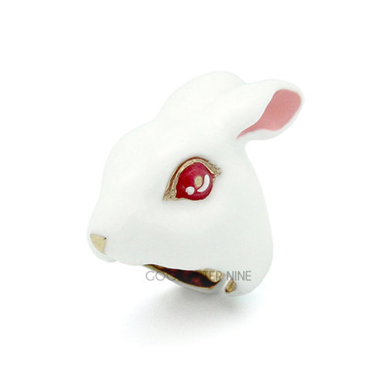 May include: White ceramic rabbit figurine with red eyes and pink ears. The rabbit's mouth is open and its teeth are visible.