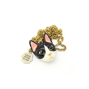 May include: A gold chain necklace with a black and white cat head charm and a small tag that says "Good After Nine".