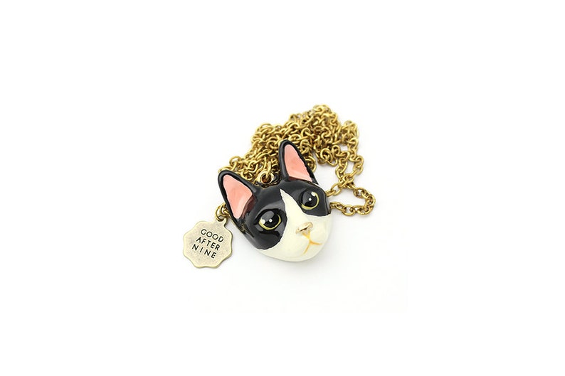 May include: A gold chain necklace with a black and white cat head charm and a small tag that says "Good After Nine".