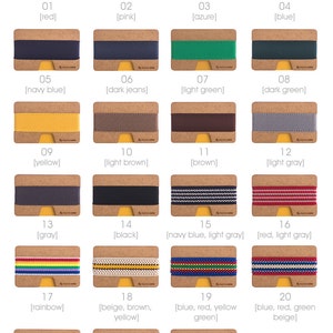 May include: A selection of 23 different colored elastic bands for a wallet. The bands are displayed on a cork background with a number and color description below each band.