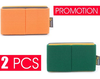 May include: Two minimalist wallets, one orange and one green, with a yellow top edge and a black interior. The wallets are made of a textured fabric and have the text "elephant wallet" printed on the side.