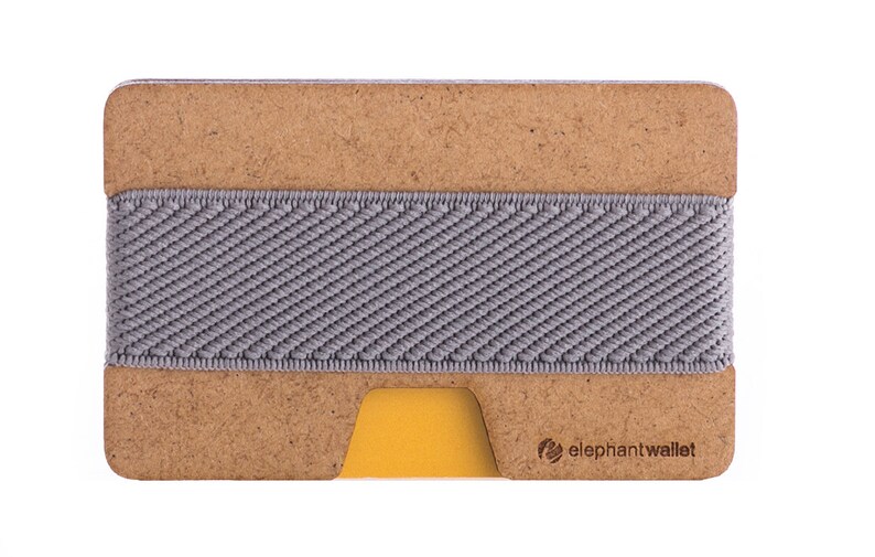 May include: A brown leather wallet with a gray elastic band and a yellow card slot. The wallet has the text "elephantwallet" printed on the bottom right corner.