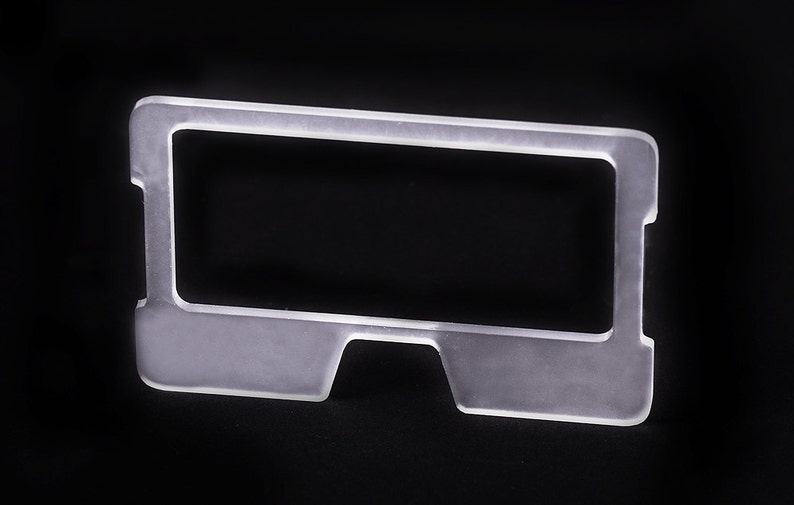 May include: A clear plastic frame with a rectangular opening. The frame has a slightly curved bottom edge.