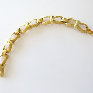 Bow link bracelet textured and polished gilded base metal with fold over clasp