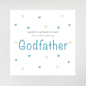 May include: A white card with blue and yellow hearts scattered across the surface. The card reads "Happy Father's Day to a very special Godfather".