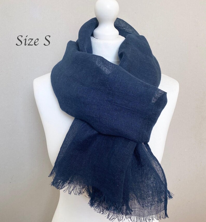 May include: A navy blue scarf with fringed edges is draped over a white mannequin. The scarf is made of a soft, woven material. The text "Size S" is in the upper left corner.