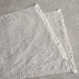 May include: Two gray linen placemats with white fringe edging.