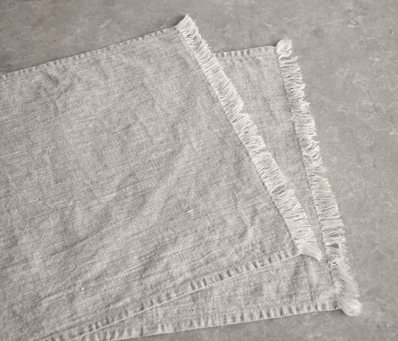 May include: Two gray linen placemats with white fringe edging.