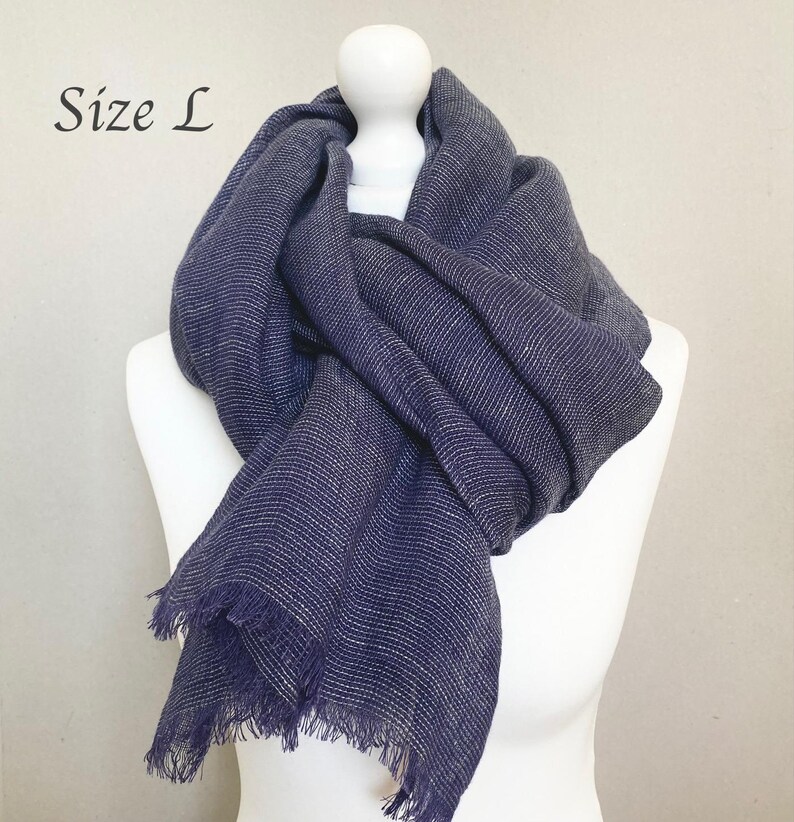May include: A navy blue scarf with white stripes and fringed edges is draped over a white mannequin. The text "Size L" is in the upper left corner. The scarf is made of a soft, woven material.