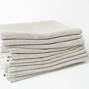 May include: A stack of 10 light gray linen napkins folded neatly. The napkins are made of a soft, natural fabric and are perfect for everyday use.