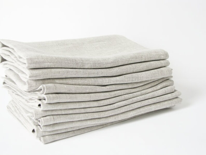 May include: A stack of 10 light gray linen napkins folded neatly. The napkins are made of a soft, natural fabric and are perfect for everyday use.