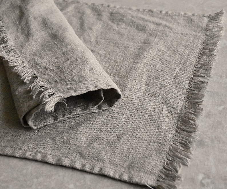 May include: A gray linen table runner with frayed edges.