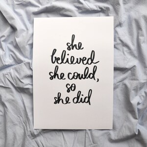 May include: A white printable poster with black handwritten text that reads "she believed she could, so she did".