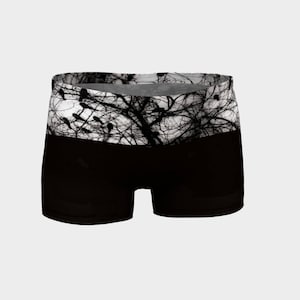 May include: Black athletic shorts with a white waistband featuring a silhouette of a tree with birds.