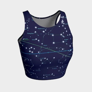 May include: A navy blue crop top with a constellation print. The constellations are outlined in white and labeled with their names. The top has a racerback style.