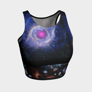 May include: A black crop top with a colorful galaxy print featuring a nebula with a pink center. The print also includes stars and other celestial bodies.