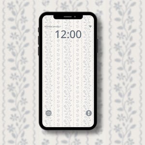 May include: A black smartphone shows a floral wallpaper with a pale blue design on a white backdrop. The time is 12:00. The phone is set against a matching floral wallpaper.