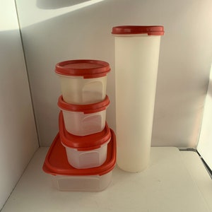 May include: Set of five clear plastic containers with red lids. The containers are stacked on top of each other, with the largest container at the bottom and the smallest container at the top. The containers are all empty.