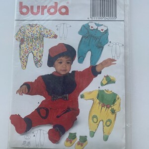 May include: A Burda baby clothing pattern packet. The packet features illustrations of baby rompers in various colors and designs, including floral, teal, and yellow. The packet also shows the sizes available: 3M, 6M, 9M, and 12M.