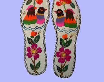 May include: Pair of white insoles with embroidered designs. Each insole features a floral and bird motif. The birds have orange, purple, and brown feathers. Red and pink flowers with green leaves are also embroidered.