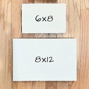 May include: Two rectangular white paper sheets with deckled edges. The top sheet features the black text 6x8, indicating dimensions of 6 by 8 inches. The bottom sheet features the black text 8x12, indicating dimensions of 8 by 12 inches.