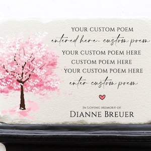 May include: A rectangular stone memorial with a pink cherry blossom tree illustration. The text includes "YOUR CUSTOM POEM" and "IN LOVING MEMORY OF DIANNE BREUER". A heart symbol is also present.