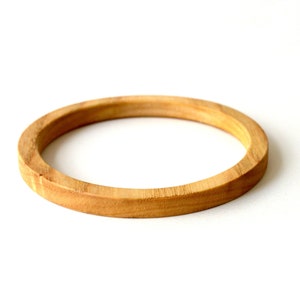 May include: A simple wooden ring, likely made from a light-colored wood like maple or birch. The ring is smooth and has a natural finish.
