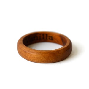 Puede incluir: Un anillo de madera marrón con la palabra "Vanilla" grabada en el interior.