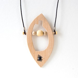 May include: A wooden pendant necklace with a leaf-shaped design. The pendant has a cutout in the shape of a heart and features a black bead and wooden beads.