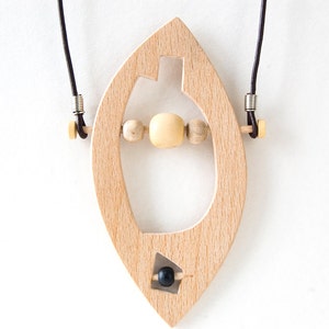 May include: A wooden pendant necklace with a leaf-shaped design. The pendant has a cutout in the shape of a bottle and features wooden beads and a black bead.