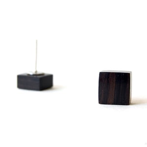 Puede incluir: Un par de pendientes cuadrados de madera negra con postes de plata.