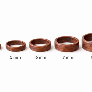 May include: Five wooden rings of varying sizes, each with a rich brown color and visible wood grain. The rings are labeled with their widths: 4 mm, 5 mm, 6 mm, 7 mm, and 8 mm. The rings are displayed against a white background.