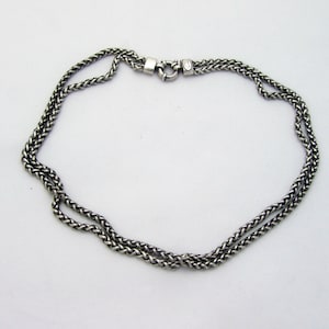 Puede incluir: Un collar de cadena de plata con un diseño de doble cadena. El collar tiene un cierre de langosta.