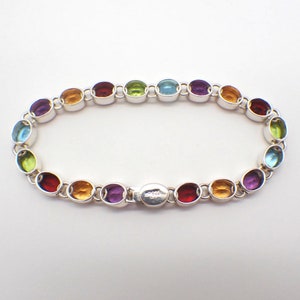 Puede incluir: Un brazalete de plata con piedras preciosas ovaladas de todos los colores del arco&iacute;ris. El brazalete tiene un cierre.