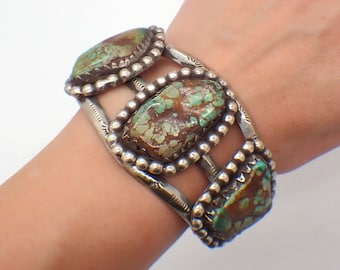 May include: A silver bracelet featuring three turquoise stones set within a beaded border. The bracelet has a wide, curved band with a decorative design.
