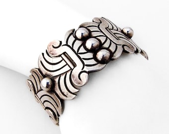 May include: A silver bracelet with a geometric design and raised round accents.