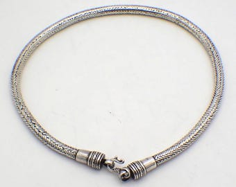 Può includere: Una collana color argento con un motivo intrecciato. La collana circolare ha una chiusura a fermaglio. Il metallo ha un aspetto leggermente invecchiato, suggerendo uno stile vintage. La collana è adatta per l'uso quotidiano o per occasioni speciali. Circonferenza di circa 40 cm.