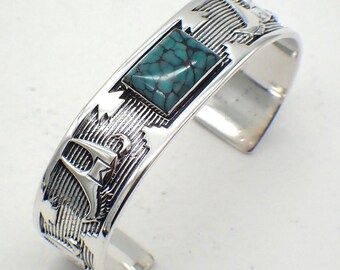 May include: A silver cuff bracelet with a turquoise stone inlay. The bracelet is decorated with a geometric design.