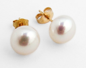 Puede incluir: Un par de pendientes de oro con perlas. Las perlas son blancas y redondas.
