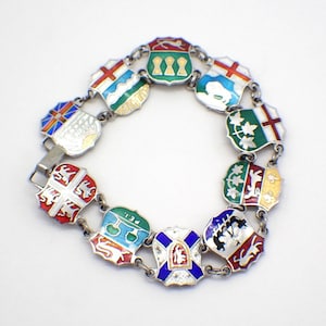 Op de afbeelding: Een zilveren armband met emaille bedels die de wapenschilden van de Canadese provincies tonen. Elke bedel is in een andere kleur en heeft een uniek ontwerp.