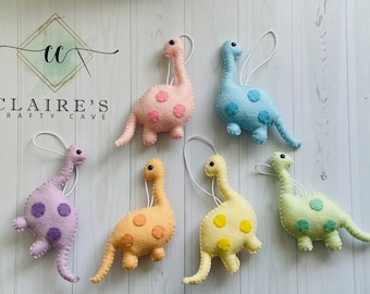 May include: Six felt dinosaur ornaments in various pastel colors with white polka dots. Each dinosaur has a loop for hanging.
