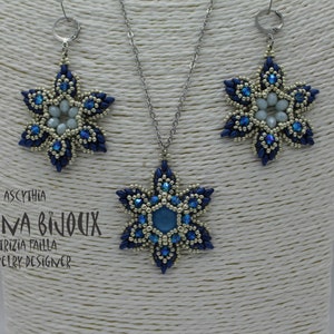 May include: A silver chain necklace with a blue and silver snowflake pendant. Matching blue and silver snowflake earrings are also pictured. The necklace and earrings are displayed on a white background.