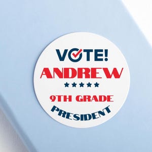 May include: A white, circular sticker with the words "VOTE! ANDREW" in red and blue. Below, it reads "9TH GRADE PRESIDENT" in red and blue. The sticker has five blue stars.