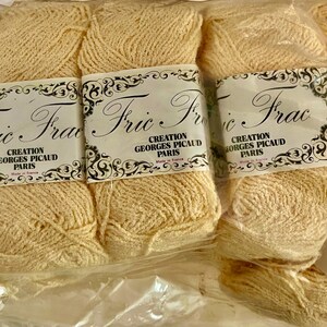 May include: A collection of light beige yarn skeins in a clear plastic bag. The labels read "Fric Frac, Creation Georges Picaud Paris". The yarn is a soft, natural colour, ideal for knitting or crochet projects.