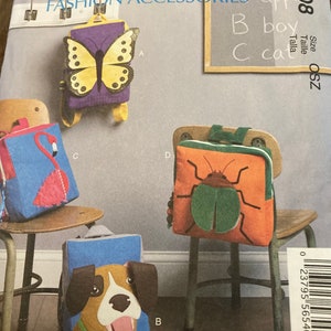 Puede incluir: Patrón de accesorios de moda McCall's con cuatro diseños de mochilas infantiles. Las mochilas incluyen una mariposa, un flamenco, un perro y un escarabajo. El patrón incluye el texto "apple", "boy" y "cat".