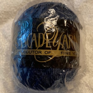 May include: A ball of navy blue yarn in clear packaging. The label, in gold, reads "Cascade Yarns, Distributor of Fine Yarns". The yarn is tightly wound and appears soft to the touch.