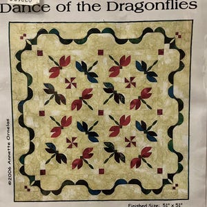 Puede incluir: Un patrón de edredón titulado "Dance of the Dragonflies", con un tamaño final de 130 cm x 130 cm. El edredón presenta un fondo amarillo claro con un patrón repetido de diseños de libélulas y cruces rojas, azules y marrones. El borde es festoneado.
