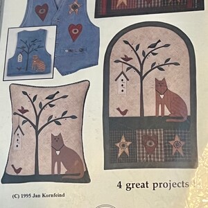 Peut inclure: Plusieurs projets d'artisanat sur le thème champêtre, avec des gilets en jean, des panneaux décoratifs et un coussin. Les motifs comprennent des appliqués en forme de cœur et d'étoile, ainsi que des motifs de chats et d'oiseaux. Le texte indique "4 great projects".